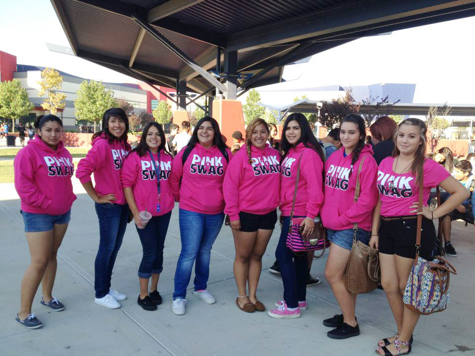 A large group of women wearing bright Pink Swag shirts at an outdoor community event